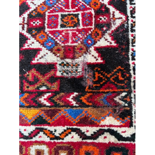 276 - A hand knotted red ground carpet/rug with geometric pattern 204cm x 295cm