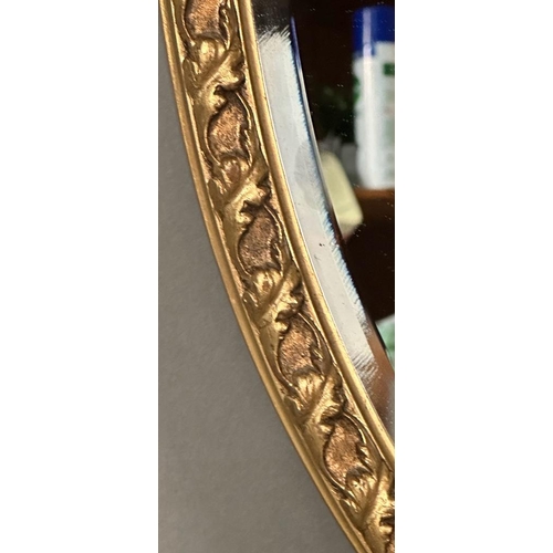 282 - An oval wooden gold painted wall hanging mirror (50cm x 71cm)