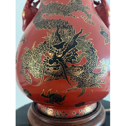 314 - A red ground Oriental vase with ornate dragon design and dragon head handles. H 44cm