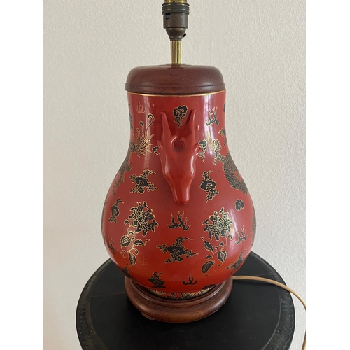 314 - A red ground Oriental vase with ornate dragon design and dragon head handles. H 44cm