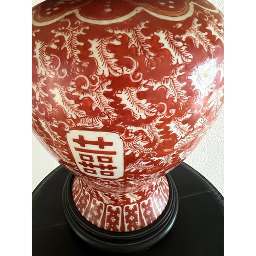 316 - An Oriental lamp base on wooden stand, red grounds H 49cm