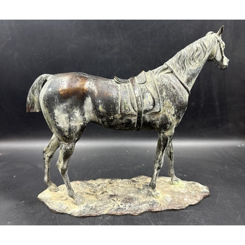 535 - A bronze of a saddled horse, unsigned (Approximate measurements 24cm H and 29cm L)