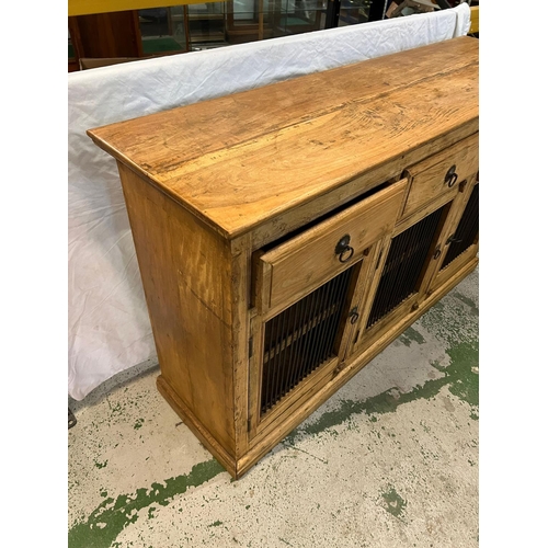 144 - A pine sideboard with three drawers and cupboards under with metal grill fronts (H91cm W153cm D45cm)