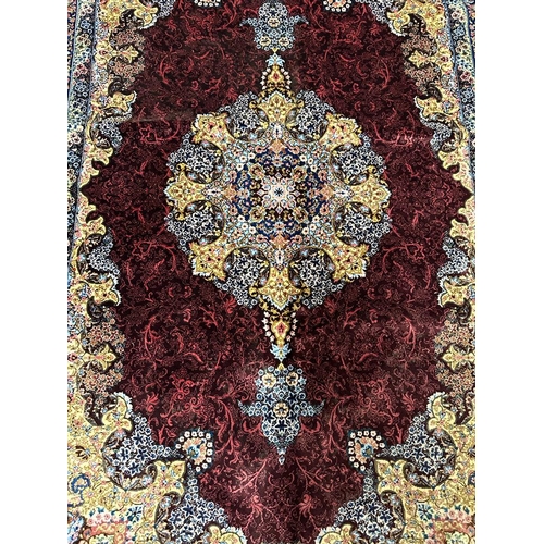 154 - A silk rug with burgandy grounds, floral border and floral central medallion 148x100