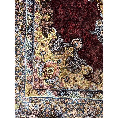 154 - A silk rug with burgandy grounds, floral border and floral central medallion 148x100