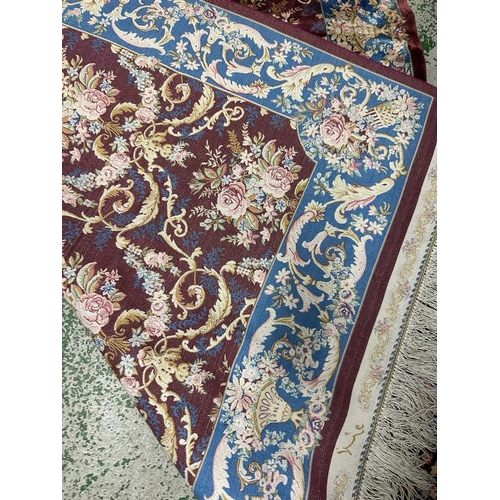 156 - A silk rug with burgandy grounds floral blue ground border and central floral motif 148x100