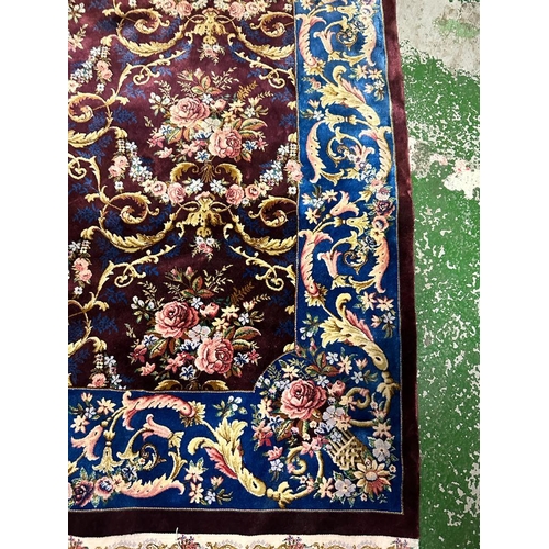 156 - A silk rug with burgandy grounds floral blue ground border and central floral motif 148x100