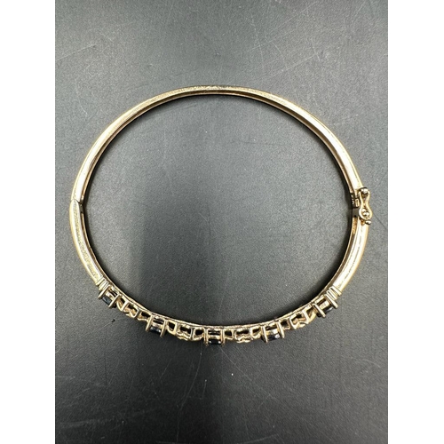 467 - A 9ct gold bangle with diamond and precious stones (7.2g)