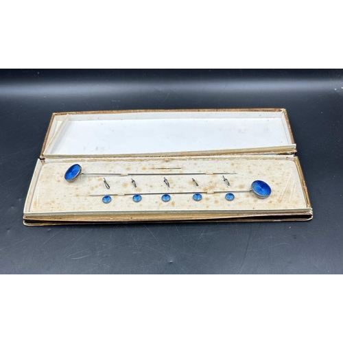 493 - An case set of blue enamel hat pins and fasteners on white metal