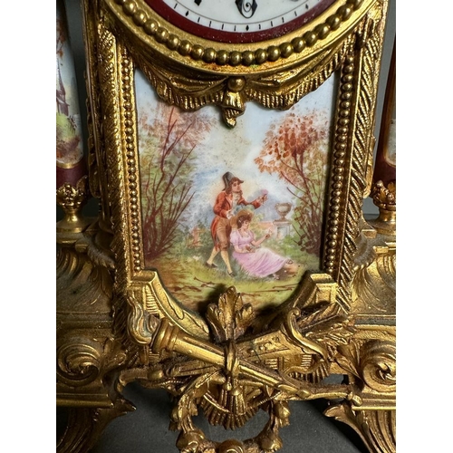 595 - A French eight day hand painted enamel faced mantel clock with garniture