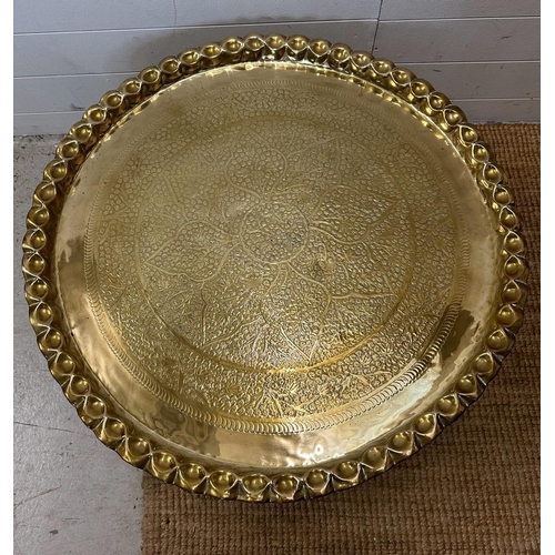 68 - A brass engraved Middle Eastern tea table on brass engraved stand. Diameter 82 height 38