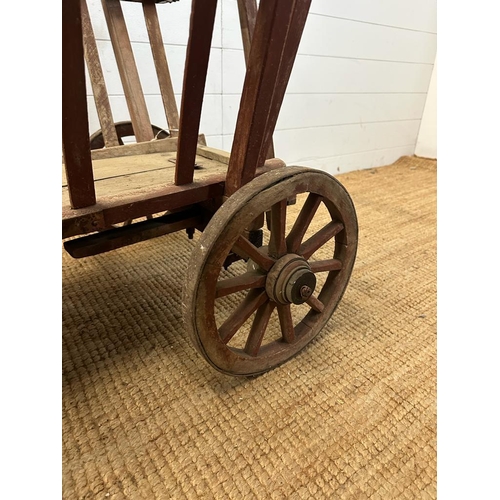 111 - A vintage wooden garden trolley on wooden metal bound wheels (H55cm W80cm D56cm)