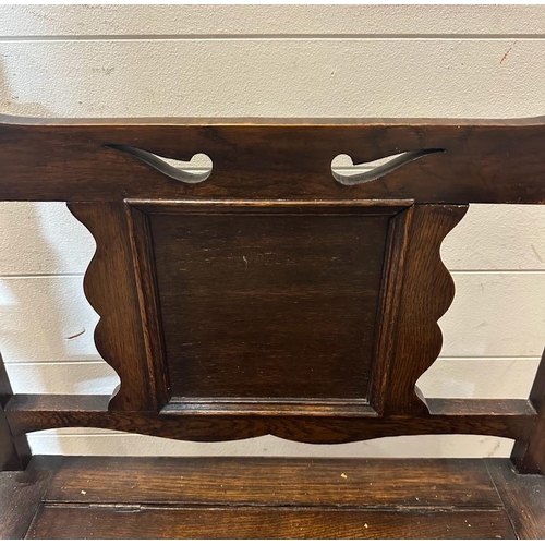 135 - An oak Arts and Crafts hall stand bench with hinged lid to reveal storage and a carved back