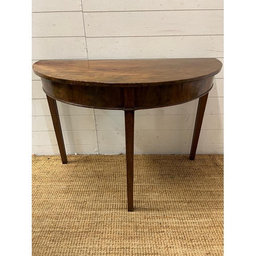 183 - A Demi Lune mahogany table on tapering legs (H74cm W108cm D51cm)