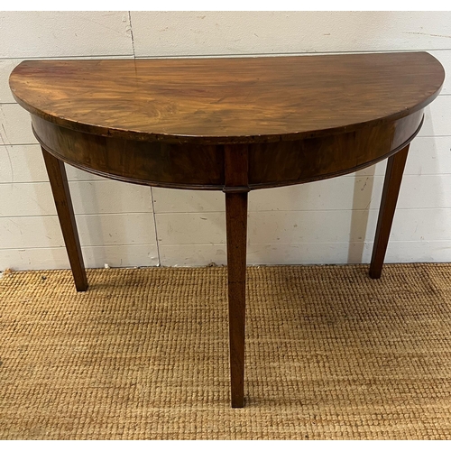 183 - A Demi Lune mahogany table on tapering legs (H74cm W108cm D51cm)