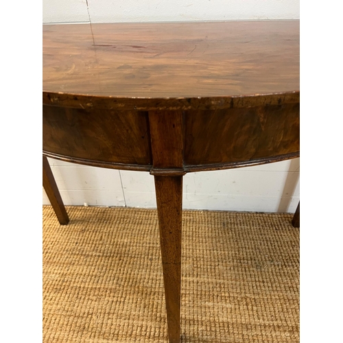 183 - A Demi Lune mahogany table on tapering legs (H74cm W108cm D51cm)