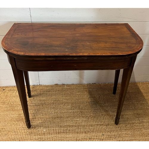 184 - A mahogany folding card table with string inlay and tapering legs (H76cm W94cm D46cm)