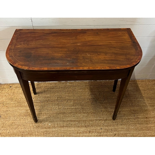 184 - A mahogany folding card table with string inlay and tapering legs (H76cm W94cm D46cm)