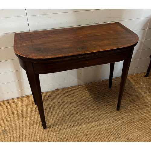 184 - A mahogany folding card table with string inlay and tapering legs (H76cm W94cm D46cm)