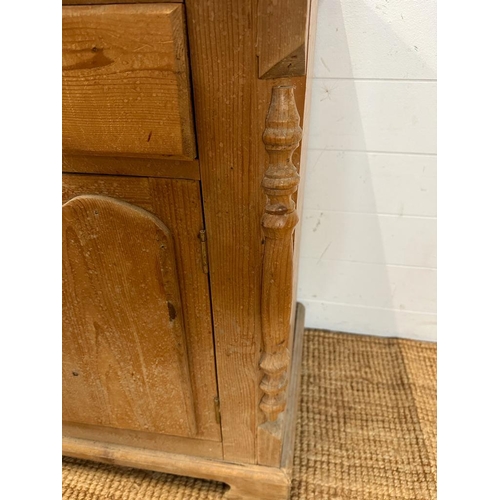 198 - A pine two drawer and two door cupboard with carved doors and supports AF (H76cm W100cm D43cm)