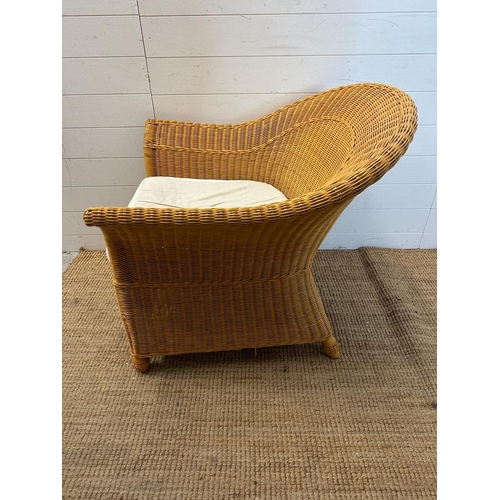 206 - A wicker arm chair with white upholstered seat cushion