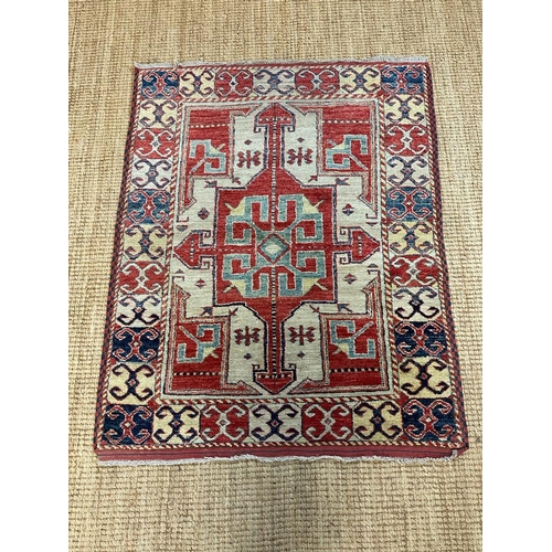 217 - A red ground rug with a repeating Aztec pattern 123cm x 100cm