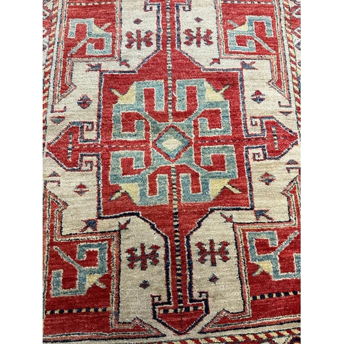 217 - A red ground rug with a repeating Aztec pattern 123cm x 100cm