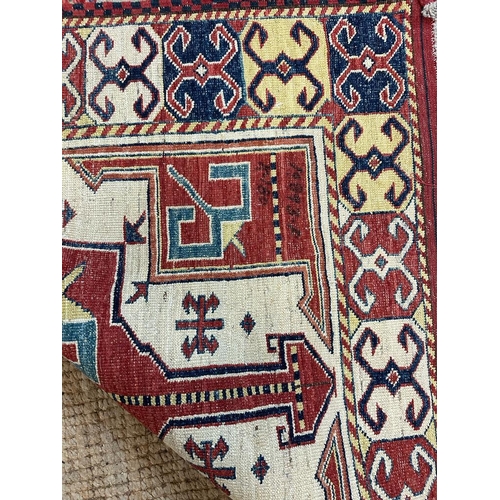 217 - A red ground rug with a repeating Aztec pattern 123cm x 100cm