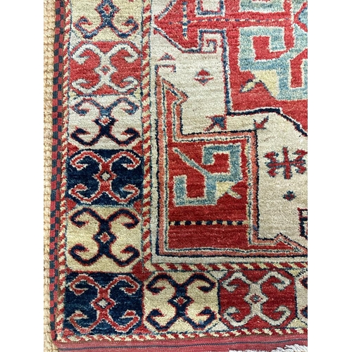 217 - A red ground rug with a repeating Aztec pattern 123cm x 100cm