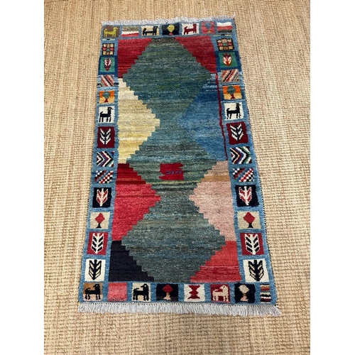 218 - A hand knotted nomad rug in greens, reds and blues 153cm x 80cm