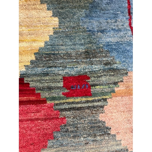 218 - A hand knotted nomad rug in greens, reds and blues 153cm x 80cm