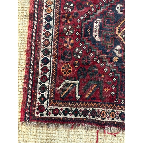 219 - A red ground rug nomadic Shiraz rug in creams, blues and oranges 110cm x 90cm