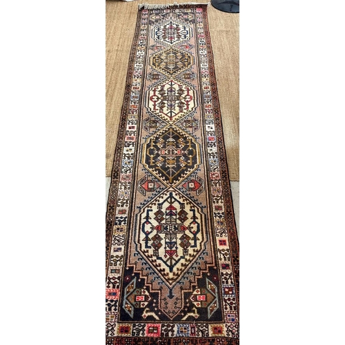 223 - A beige ground wool runner with geometric boarder and Aztec style central 75cm x 309cm