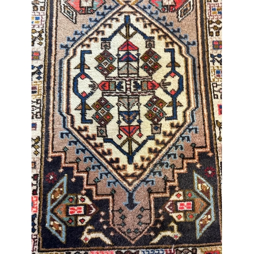 223 - A beige ground wool runner with geometric boarder and Aztec style central 75cm x 309cm