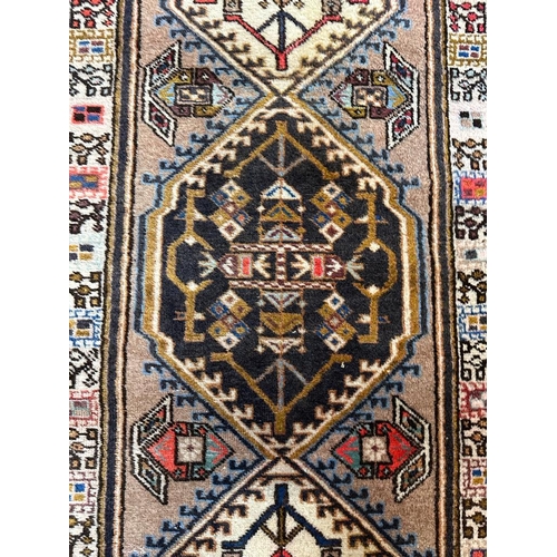 223 - A beige ground wool runner with geometric boarder and Aztec style central 75cm x 309cm