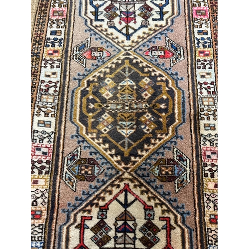 223 - A beige ground wool runner with geometric boarder and Aztec style central 75cm x 309cm