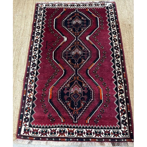 224 - A red ground wool rug with cream and blue geometric boarder 166cm x 110cm