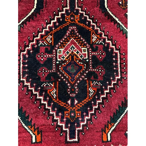 224 - A red ground wool rug with cream and blue geometric boarder 166cm x 110cm