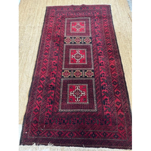 225 - A red ground wool rug with geometric central medallions