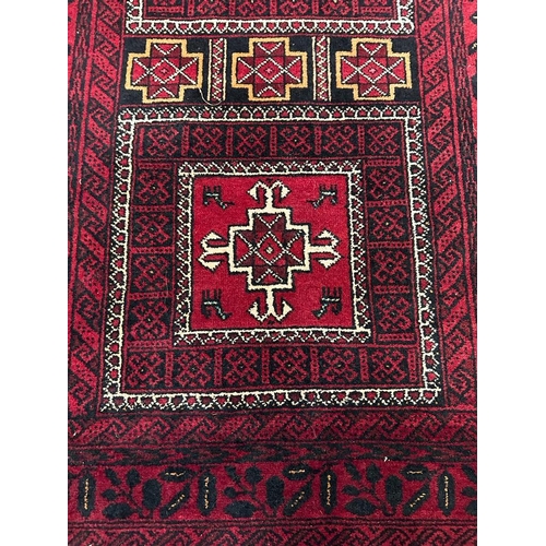 225 - A red ground wool rug with geometric central medallions