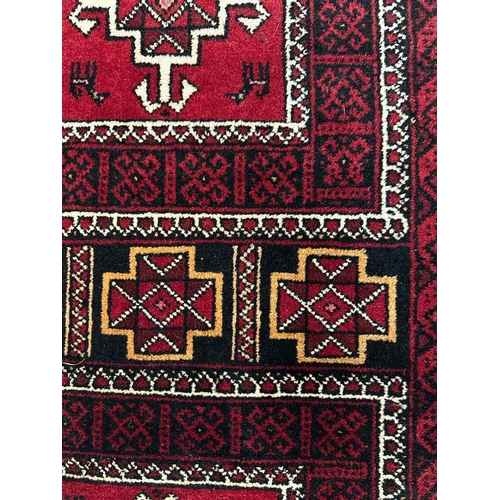 225 - A red ground wool rug with geometric central medallions