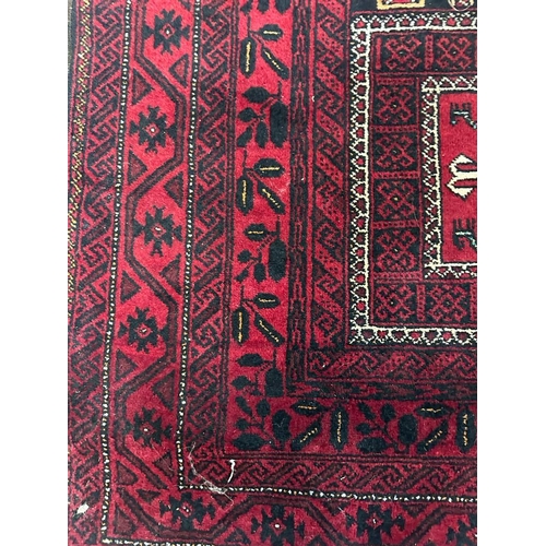 225 - A red ground wool rug with geometric central medallions