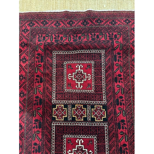 225 - A red ground wool rug with geometric central medallions