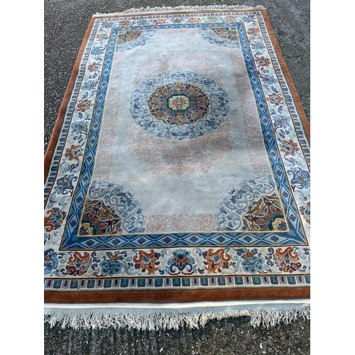 227 - A beige ground wool rug with geometric border and blue and red central medallion 280cm x 180cm