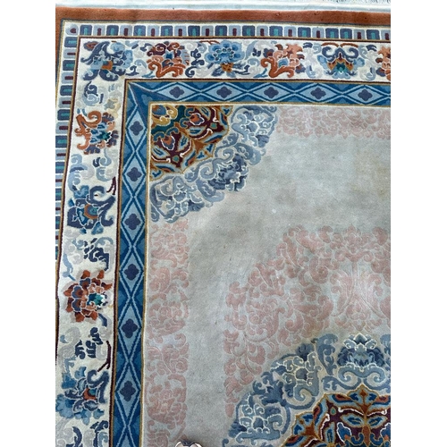 227 - A beige ground wool rug with geometric border and blue and red central medallion 280cm x 180cm