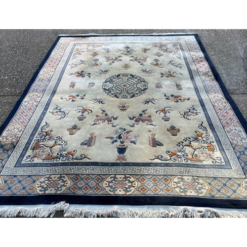 228 - A large beige ground rug with a blue boarder and central medallion 276cm x 386cm