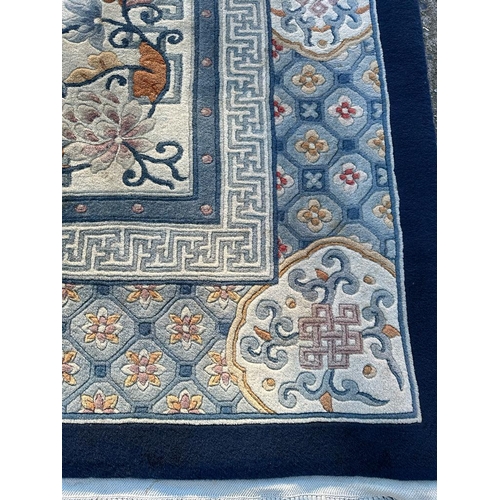 228 - A large beige ground rug with a blue boarder and central medallion 276cm x 386cm