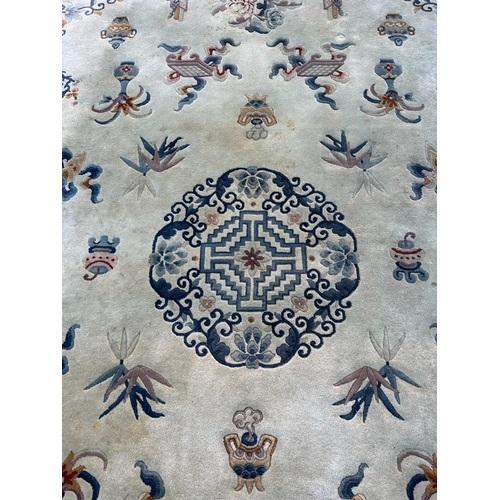 228 - A large beige ground rug with a blue boarder and central medallion 276cm x 386cm