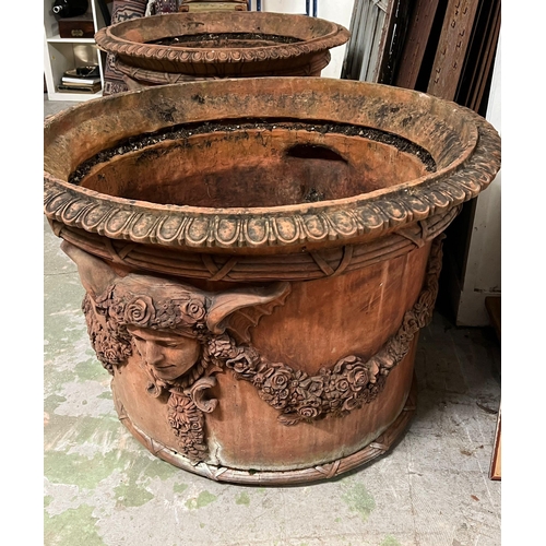 266 - A pair of ornamental terracotta urns with classical style, decorated with a floral laurel joined by ... 