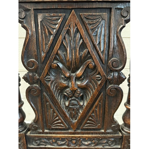 36 - A single oak Jacobean style hall chair with a carved lion back and turned supports finishing in deco... 